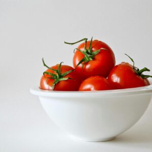 Vibrant red tomatoes in a white bowl, emphasizing freshness and simplicity.